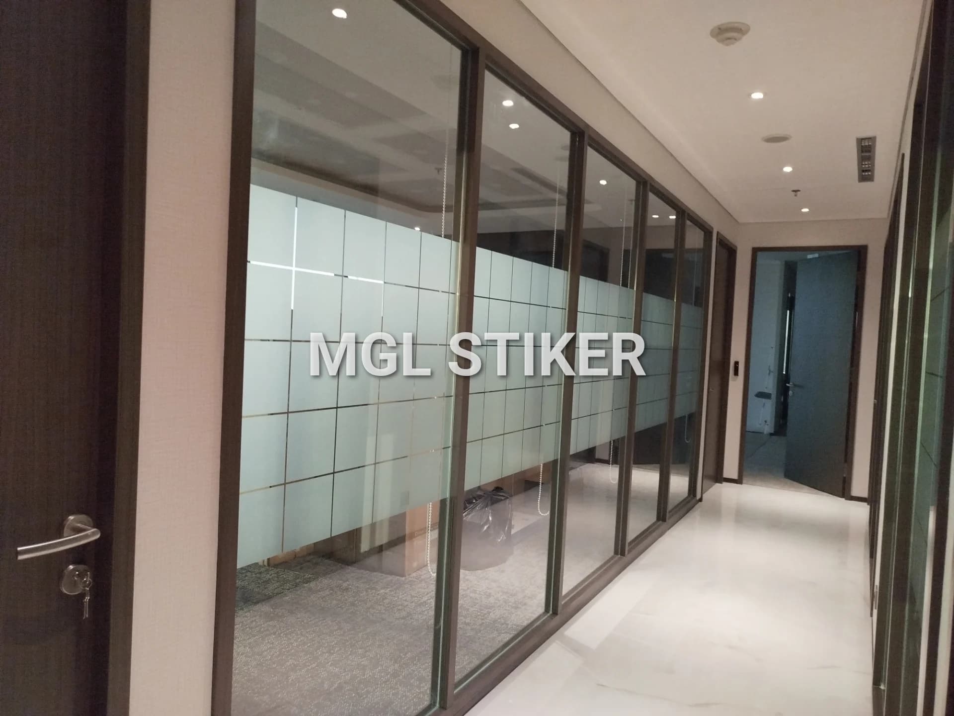Aplikasi Stiker Sandblast Cutting dengan desain kotak-kotak pada partisi kaca di area kantor, memberikan privasi dan estetika modern. Solusi berkualitas dari MGL Stiker untuk proyek Adaro Sandblast.